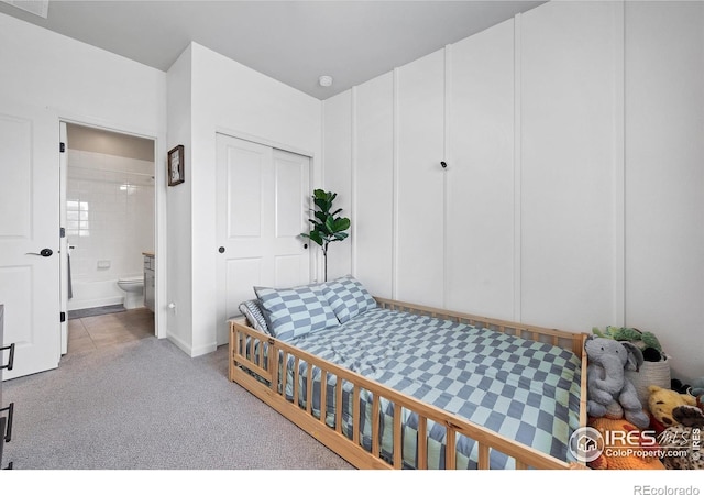 bedroom featuring ensuite bath, a closet, and light colored carpet