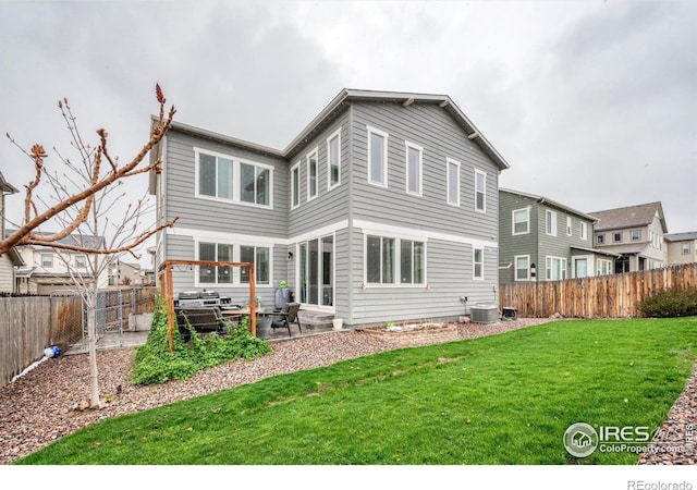 back of property with central air condition unit, a patio area, a lawn, and a fenced backyard
