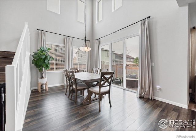 dining room with dark wood-type flooring, stairway, a wealth of natural light, and baseboards