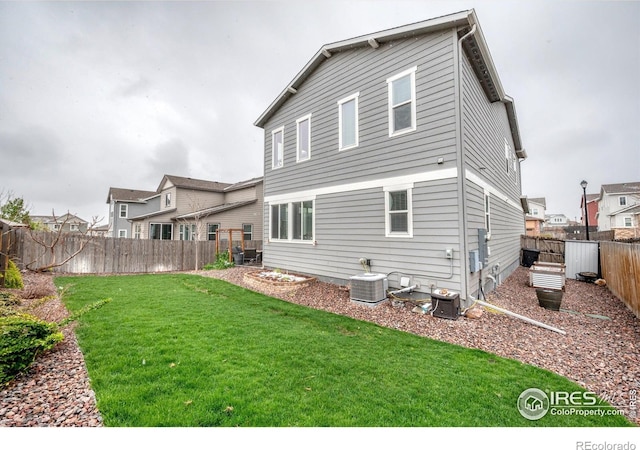 back of house with a fenced backyard, a yard, and cooling unit
