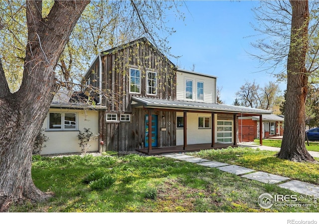 view of front of property with board and batten siding, a porch, metal roof, and a front yard