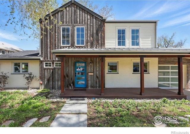 view of front of house with covered porch, brick siding, and board and batten siding