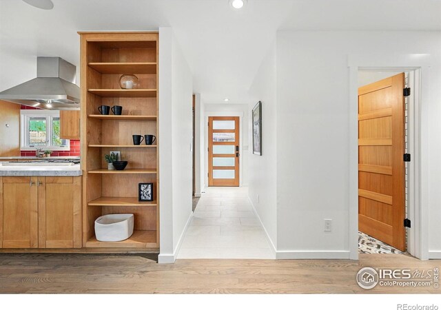 hallway with baseboards, light wood finished floors, and recessed lighting