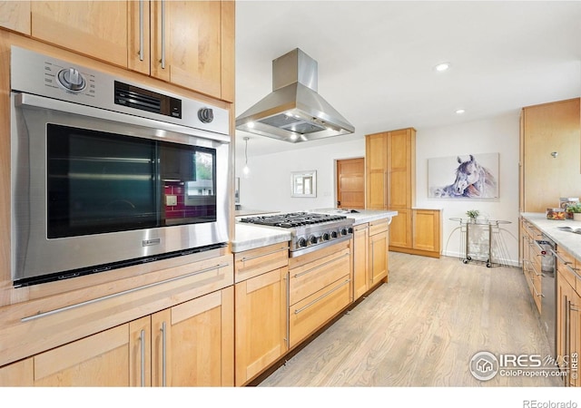 kitchen with island range hood, light countertops, light brown cabinets, stainless steel appliances, and light wood-style flooring
