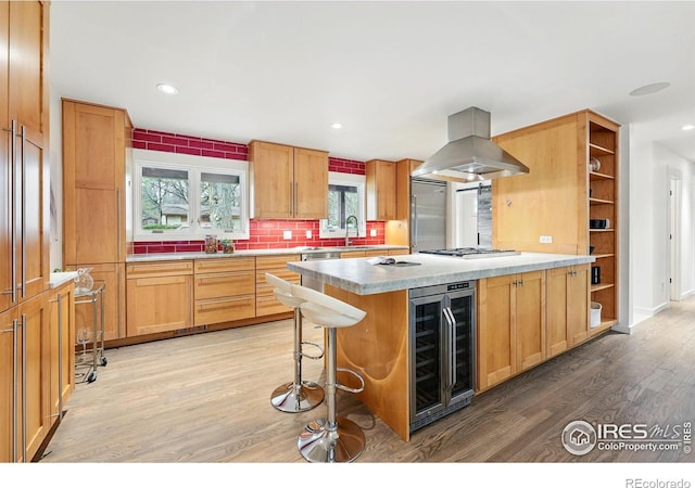 kitchen featuring open shelves, appliances with stainless steel finishes, beverage cooler, island exhaust hood, and light wood-type flooring