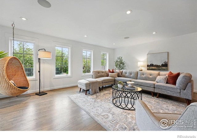 living area with recessed lighting, baseboards, wood finished floors, and a healthy amount of sunlight