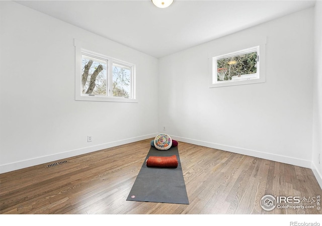 workout room with baseboards, visible vents, and wood finished floors