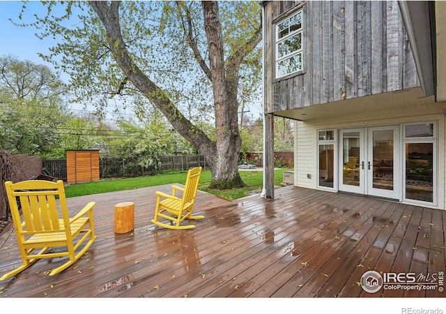 wooden terrace featuring a lawn, a fenced backyard, and french doors