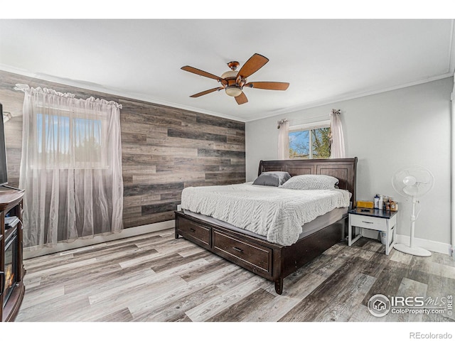 bedroom with light wood-style floors, ornamental molding, a ceiling fan, and wood walls