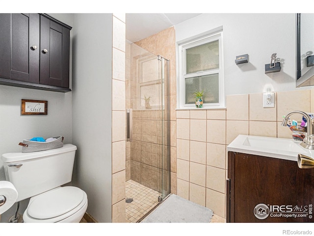 full bath with vanity, toilet, tile walls, and a stall shower