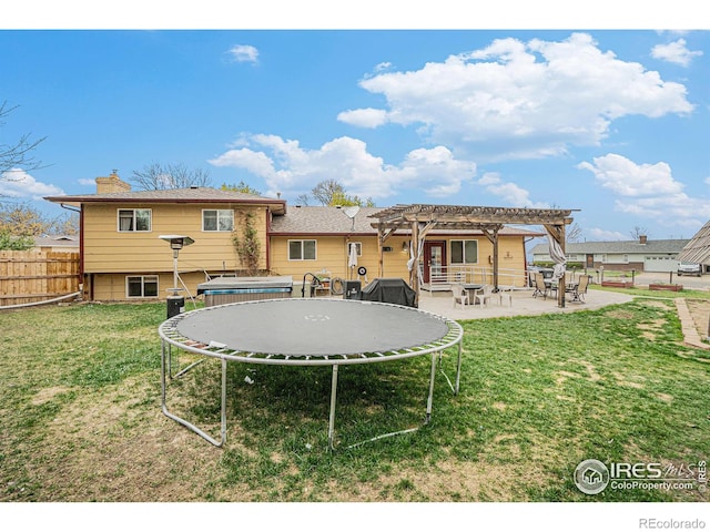 back of house with fence, a pergola, a patio, a trampoline, and a yard