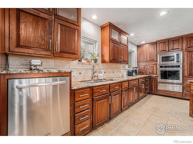 kitchen featuring backsplash, a sink, glass insert cabinets, a warming drawer, and stainless steel appliances
