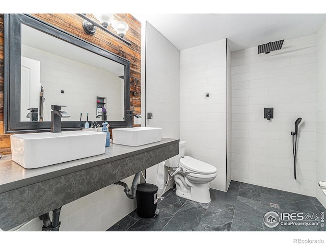 bathroom featuring tile walls, a tile shower, and toilet