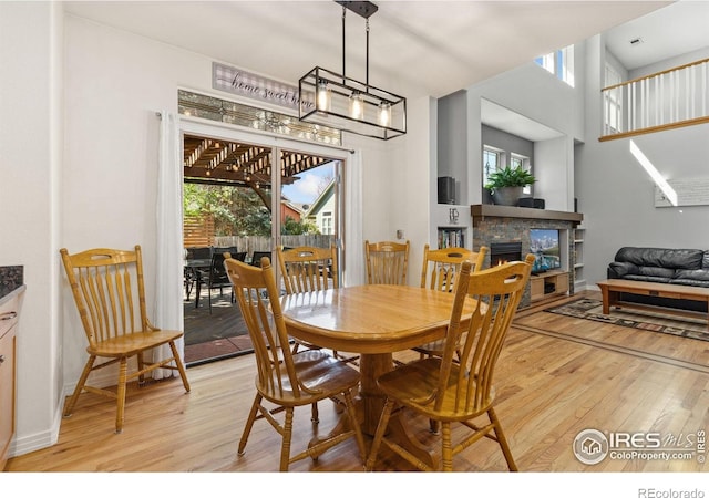 dining room with a healthy amount of sunlight, a lit fireplace, and light wood finished floors