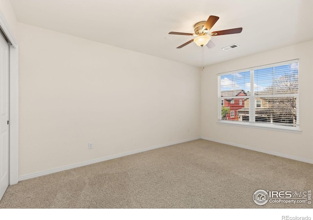 spare room with carpet floors, a ceiling fan, baseboards, and visible vents