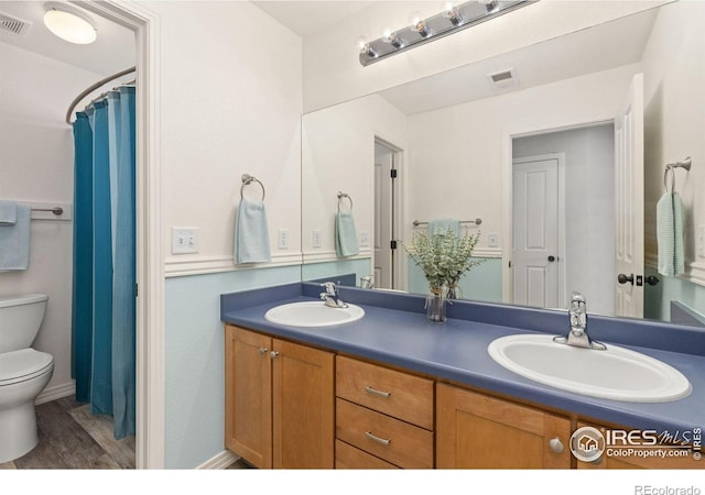 bathroom featuring double vanity, toilet, visible vents, and a sink