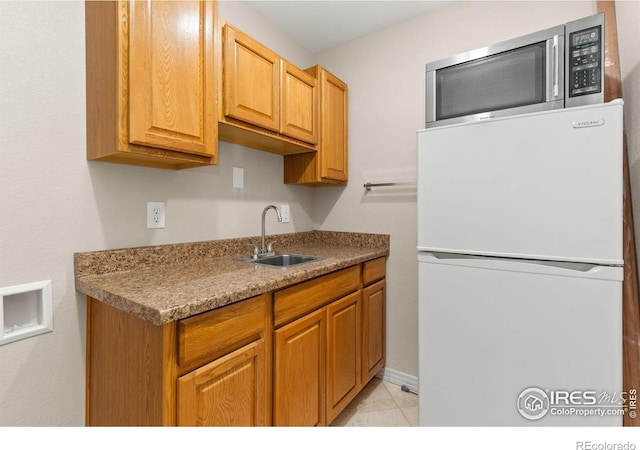kitchen with a sink, freestanding refrigerator, and stainless steel microwave