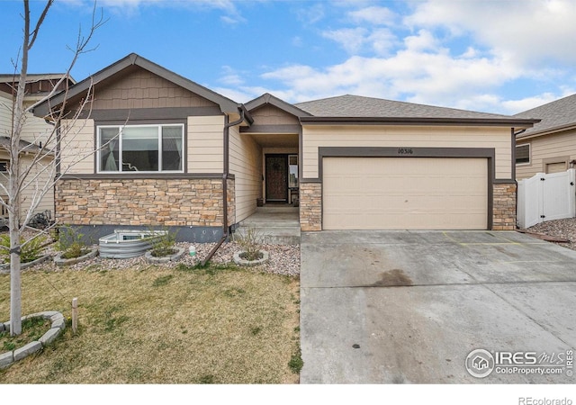 view of front of home with concrete driveway, an attached garage, fence, and stone siding