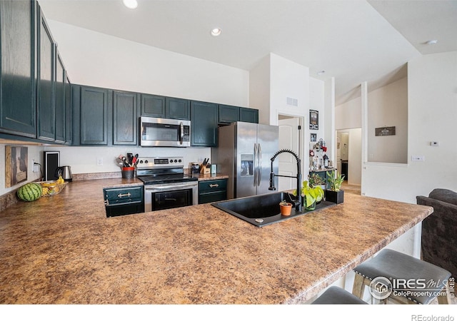 kitchen featuring stainless steel appliances, a kitchen breakfast bar, a peninsula, a sink, and a towering ceiling