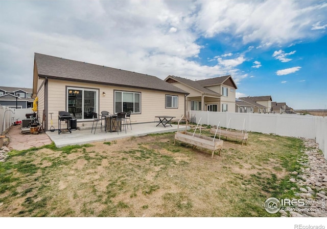 back of house with a fenced backyard, a patio area, a lawn, and a vegetable garden