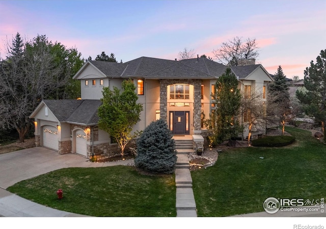 traditional-style home featuring stucco siding, an attached garage, concrete driveway, stone siding, and a front yard