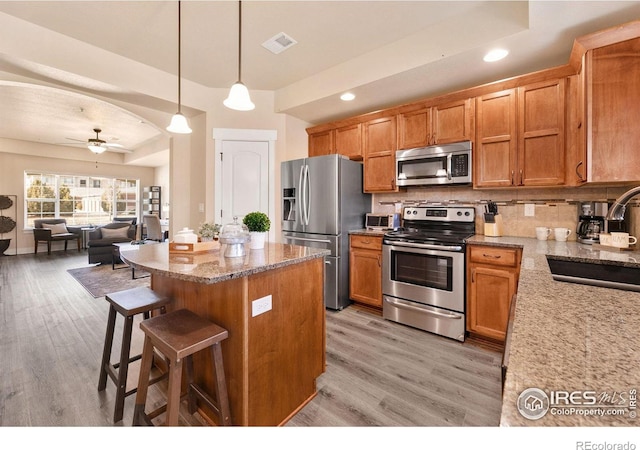 kitchen with light wood finished floors, visible vents, a sink, appliances with stainless steel finishes, and open floor plan