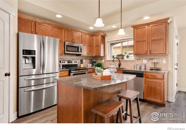 kitchen with a sink, wood finished floors, stainless steel appliances, backsplash, and recessed lighting