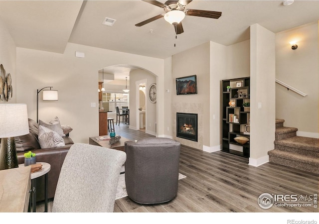 living room with arched walkways, baseboards, wood finished floors, stairs, and ceiling fan