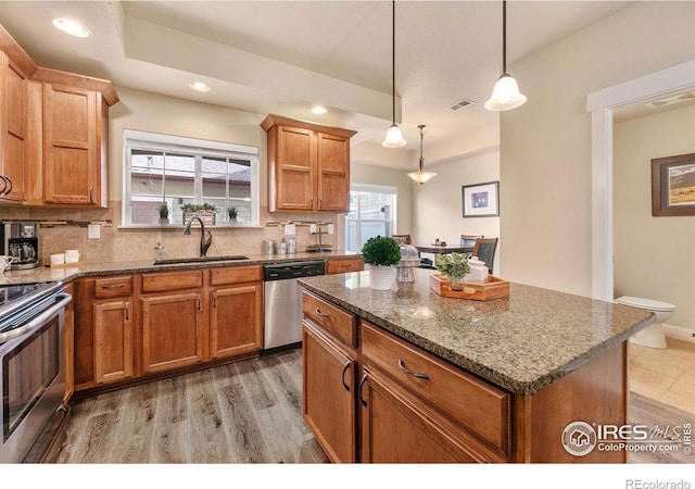 kitchen featuring a center island, a sink, visible vents, decorative backsplash, and appliances with stainless steel finishes