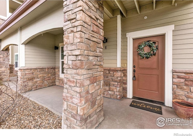 doorway to property featuring stone siding and a porch