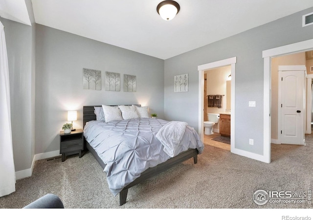 carpeted bedroom featuring ensuite bath, baseboards, and visible vents