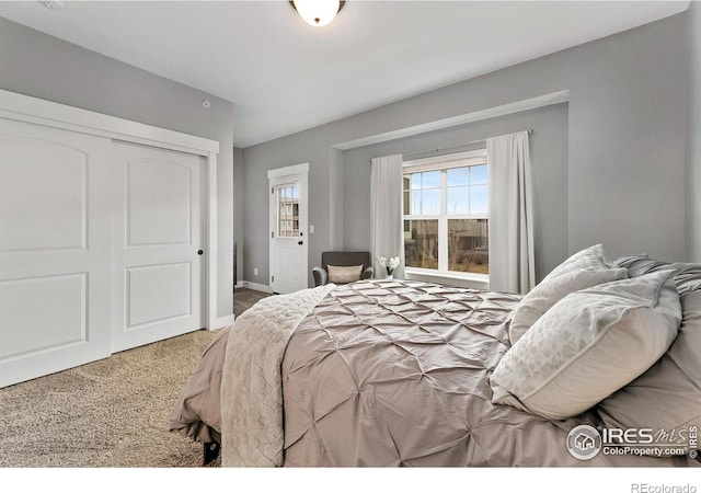 carpeted bedroom featuring baseboards and a closet