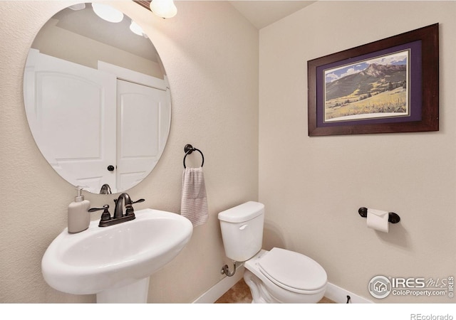 bathroom featuring baseboards, a sink, and toilet