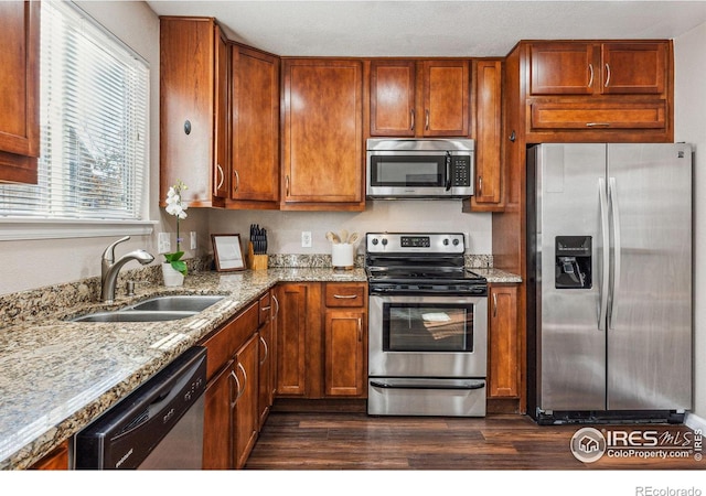 4774 Coker Ave, Castle Rock, CO 80104 - kitchen featuring stainless steel appliances, a sink, dark wood-type flooring, light stone counters, and brown cabinets