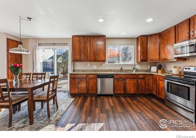 4774 Coker Ave, Castle Rock, CO 80104 - kitchen featuring appliances with stainless steel finishes, dark wood finished floors, brown cabinetry, a textured ceiling, and light stone counters