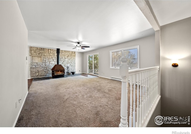 17492 County Road 29, Brush, CO 80723 - unfurnished living room with baseboards, carpet flooring, a wood stove, and ceiling fan