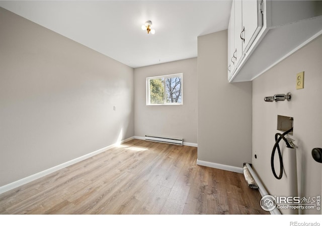 17492 County Road 29, Brush, CO 80723 - washroom with wood finished floors, a baseboard heating unit, cabinet space, baseboards, and washer hookup