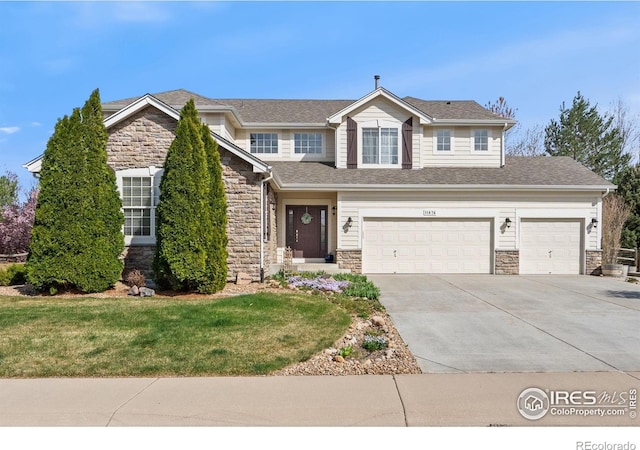 traditional-style home with a garage, concrete driveway, a front yard, and stone siding