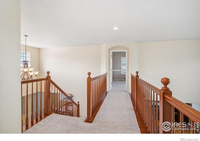 hall with recessed lighting, carpet, a notable chandelier, and an upstairs landing