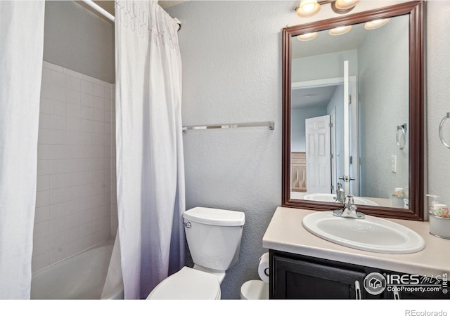 full bathroom with vanity, a textured wall, toilet, and shower / tub combo