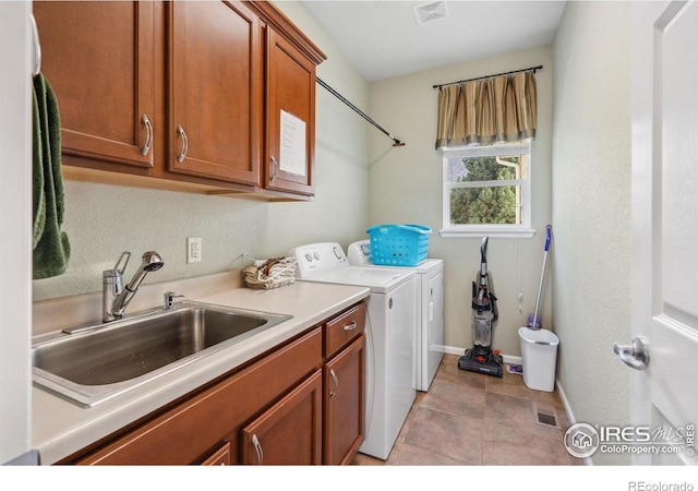 laundry room featuring cabinet space, a sink, baseboards, visible vents, and washing machine and dryer