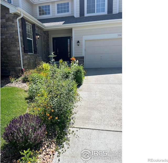 11676 Montgomery Cir, Longmont, CO 80504 - entrance to property with a garage, concrete driveway, stone siding, and roof with shingles