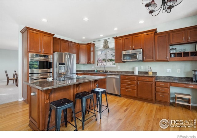 11676 Montgomery Cir, Longmont, CO 80504 - kitchen featuring appliances with stainless steel finishes, a kitchen bar, light wood finished floors, recessed lighting, and a chandelier