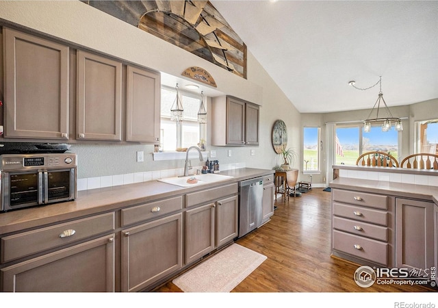 2190 Coyote Creek Dr, Fort Lupton, CO 80621 - kitchen with a sink, dishwasher, vaulted ceiling, wood finished floors, and plenty of natural light