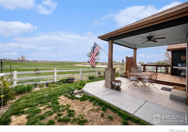 2190 Coyote Creek Dr, Fort Lupton, CO 80621 - view of patio / terrace featuring ceiling fan, fence, a deck, outdoor dining area, and a rural view
