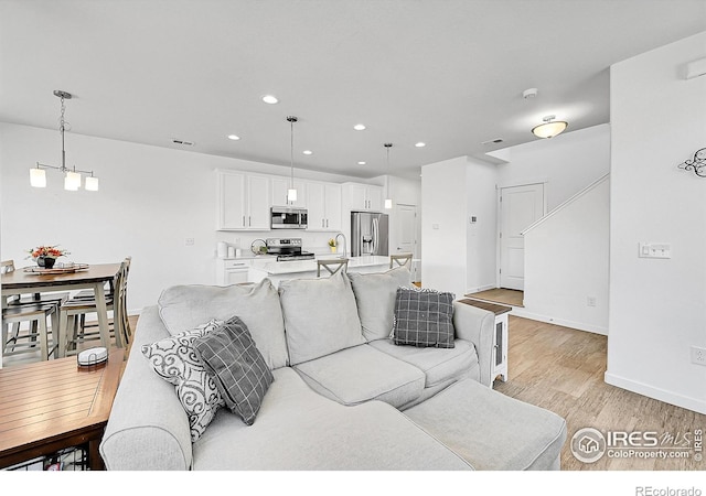 living area with light wood-style flooring, visible vents, an inviting chandelier, baseboards, and recessed lighting