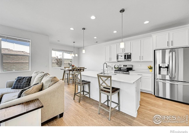 kitchen with recessed lighting, stainless steel appliances, a sink, a kitchen bar, and open floor plan