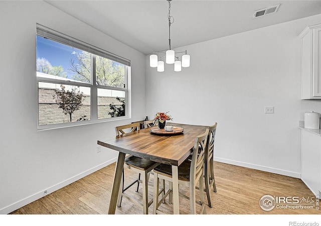 dining area with baseboards, light wood-style flooring, and visible vents