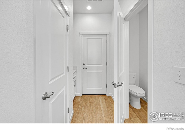 bathroom with toilet, visible vents, recessed lighting, wood finished floors, and a textured wall