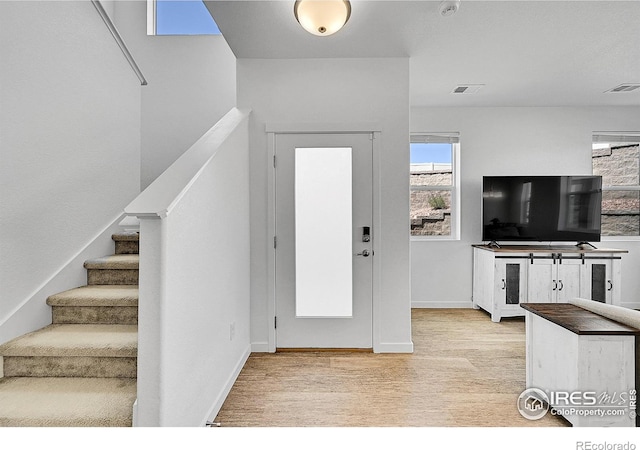 foyer entrance featuring stairway, baseboards, wood finished floors, and visible vents